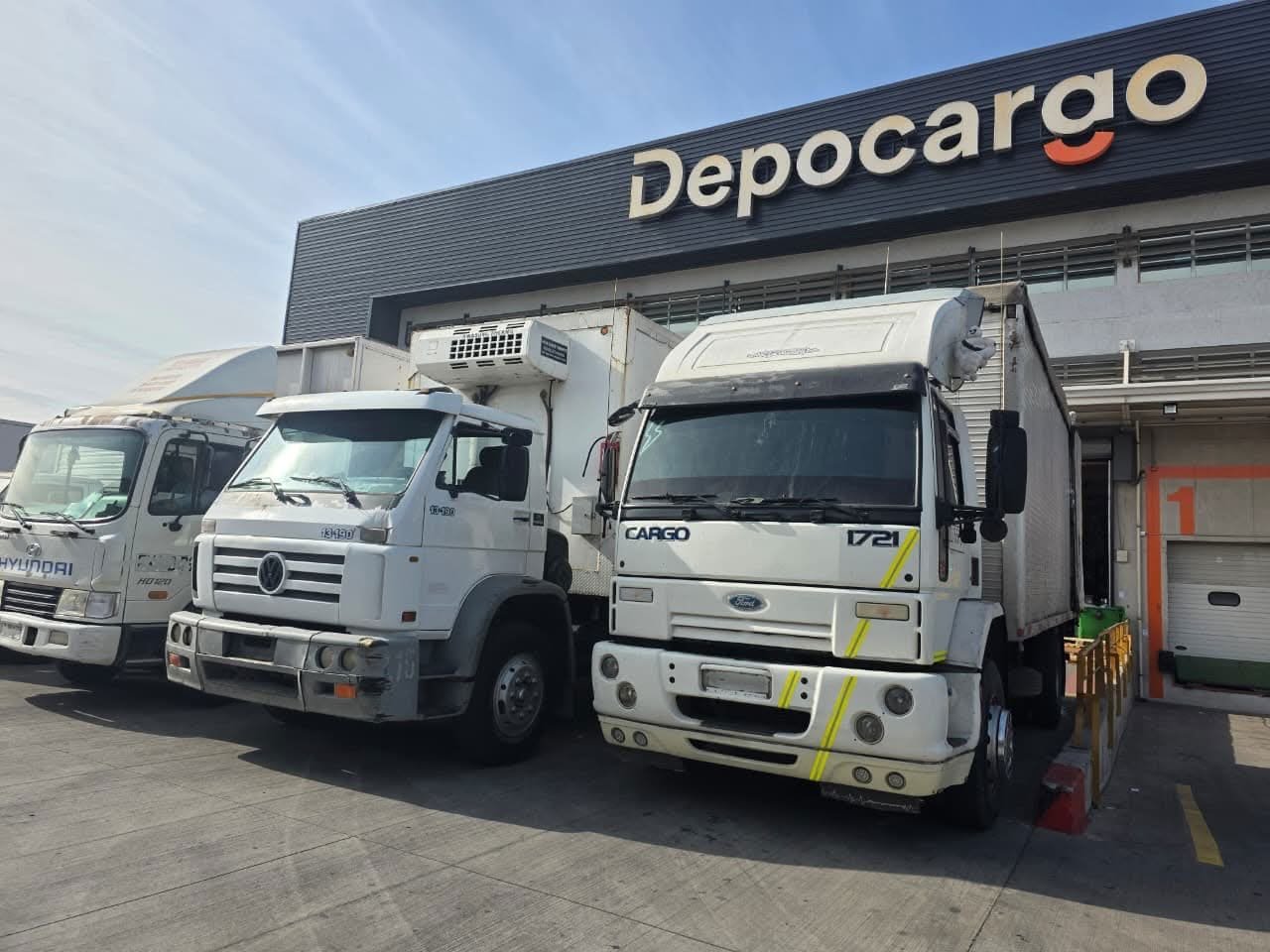 Camiones de caja cerrada de Transportes KMP estacionados en la bodega del cliente Depocargo