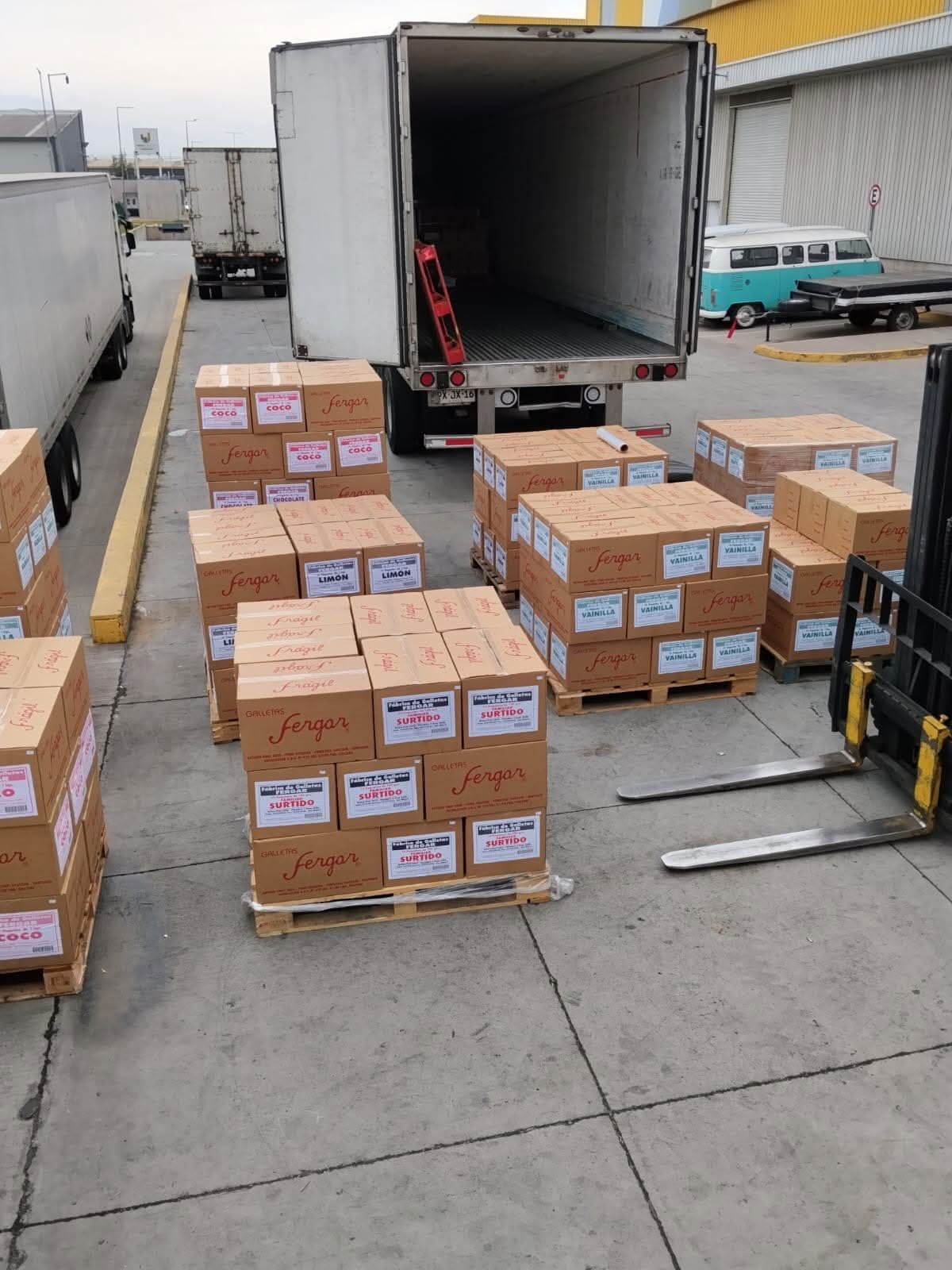 Pallets de Galletas Fergar en el patio junto a un camión abierto y una grúa horquilla